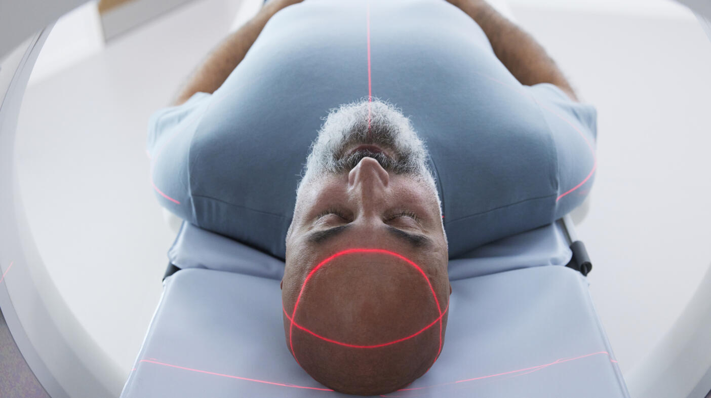 Man lying down with eyes closed inside a medical scanner