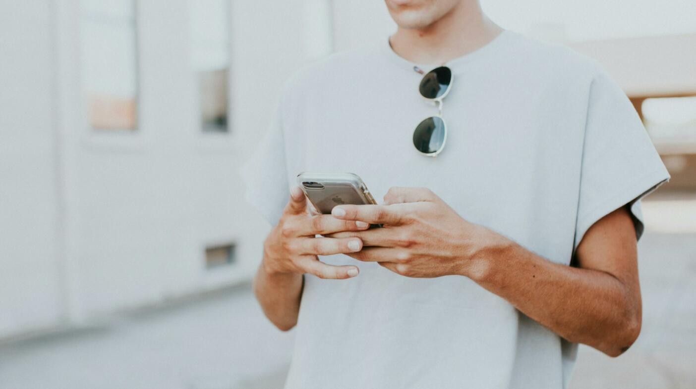 Man looking down at the iPhone he is holding in his hands