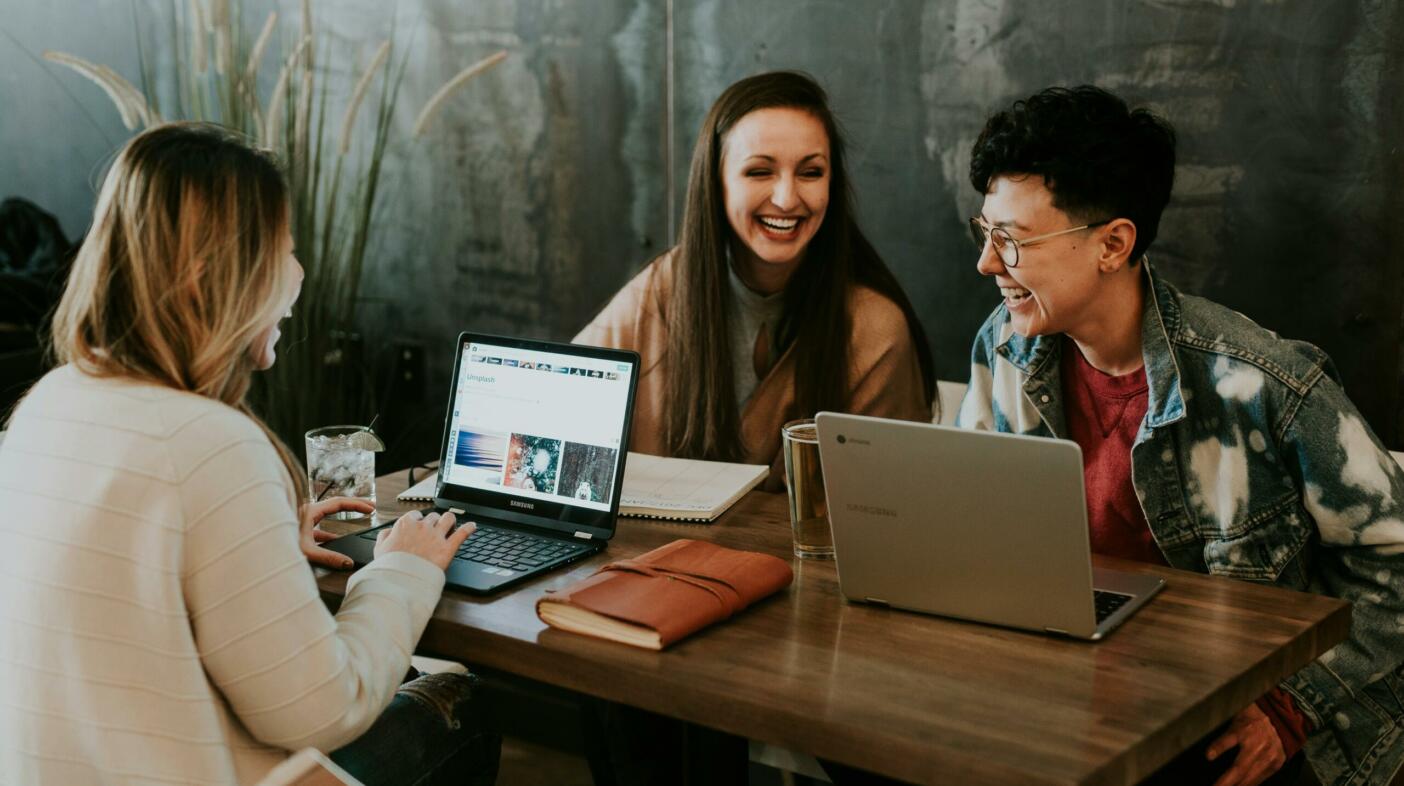 Three people sat in front of laptops and notebooks